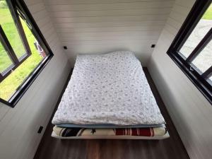 a bed in a tiny house with two windows at Microen in Stryn