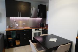 een keuken met zwarte kasten en een tafel met stoelen bij Charmant Appartement au Pré in Pré Saint Gervais