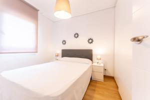 a white bedroom with a bed and a window at luminoso apartamento en maliaño in Maliaño