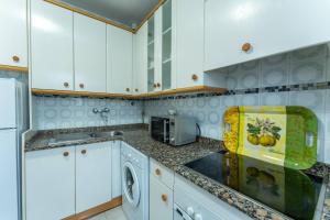 a kitchen with white cabinets and a washer and dryer at luminoso apartamento en maliaño in Maliaño