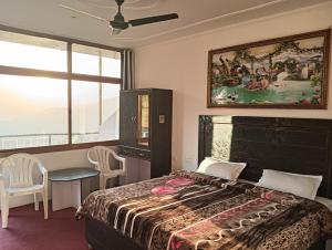een slaapkamer met een bed en een schilderij aan de muur bij Amazing view in McLeod Ganj
