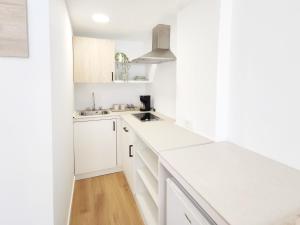 a white kitchen with white cabinets and a sink at Flacalco Hotel & Apartments in Cala Ratjada