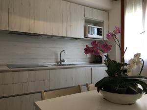 a kitchen with a table with a vase of flowers on it at Casa Eva in Bibione