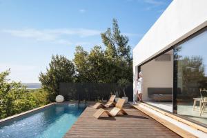 a house with a swimming pool and a woman standing on a deck at AB61 Tiny Design House for Two in Jadranovo