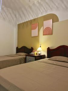 1 dormitorio con 2 camas y mesa con lámpara en Quoc Dinh Guesthouse, en Mui Ne