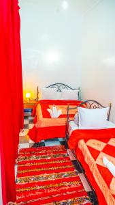 two beds in a room with red curtains at Hotel imouzzer in Marrakech