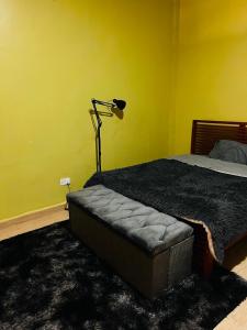 a bedroom with a bed and a lamp on a yellow wall at The home hive apartment in Kampala