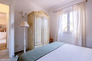 a white bedroom with a bed and a window at Orosei Home Holidays - Sa Vadde in Cala Liberotto
