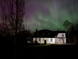 a white house with the aurora in the sky at Auberge musicale Pour un Instant in La Malbaie