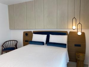 a bedroom with a white bed with two blue pillows at Tramonto Maisonettes & Suites in Parga