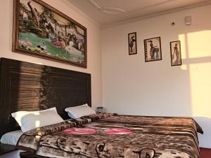 een slaapkamer met een bed met een deken en foto's aan de muur bij Amazing view in McLeod Ganj