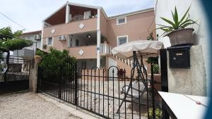 a fence with an umbrella in front of a building at apartmani G&M in Bibinje