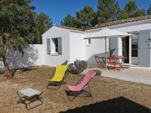 eine Terrasse mit 2 Stühlen, einem Tisch und einem Sonnenschirm in der Unterkunft La Grande Margotte by Edgar et Alfred in Saint-Georges-dʼOléron