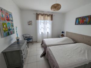 ein Schlafzimmer mit zwei Betten und einem Fenster in der Unterkunft La Grande Margotte by Edgar et Alfred in Saint-Georges-dʼOléron