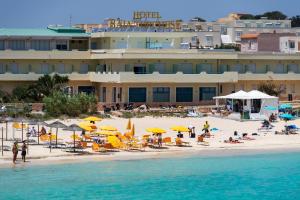 ein Strand mit gelben Sonnenschirmen und Menschen am Strand in der Unterkunft Hotel Baia Turchese in Lampedusa