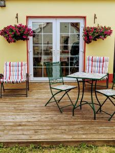 twee stoelen en een tafel op een veranda met bloemen bij Luxury 3 bedroom house with peaceful garden, sleeps 6 and 2 mins to beach in Bundoran