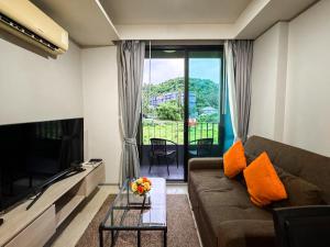 a living room with a couch and a television at Comfy 1 Bedroom Condo in Surin (Seaview Rooftop Pool & Gym) in Phuket Town