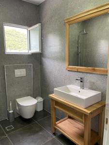 a bathroom with a sink and a toilet and a mirror at Hotel Jali in Himare