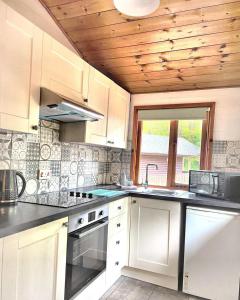 uma cozinha com armários brancos e um tecto de madeira em Magpie 2 Hot Tub HuntersMoon-Warminster-Longleat-Wiltshire em Warminster