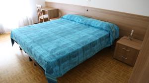 um quarto com uma cama com um edredom azul em ALBERGO AL CACCIATORE em Paluzza