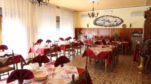 uma sala de jantar com mesas e cadeiras com toalhas de mesa vermelhas em ALBERGO AL CACCIATORE em Paluzza