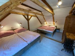 2 łóżka w sypialni na poddaszu z drewnianymi sufitami w obiekcie Apartmány u Dostálů w mieście Bedřichov