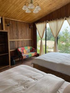 1 dormitorio con 2 camas, silla y ventana en Retro House Mộc Châu, en Mộc Châu