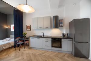 a kitchen with a refrigerator and a table and a bed at Art Apartment in Toruń