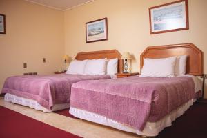 um quarto de hotel com duas camas com cobertores roxos em Hotel Mosul em Concepción