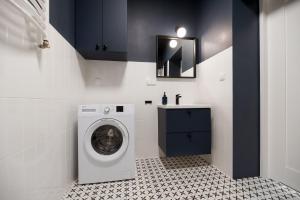 a laundry room with a washing machine and a sink at Art Apartment in Toruń
