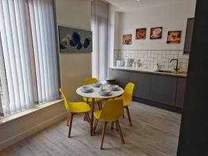 a kitchen with a table and yellow chairs in a room at Suffolk House Apartments HU1 in Hull