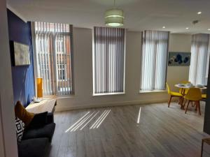 a living room with a table and chairs and windows at Suffolk House Apartments HU1 in Hull