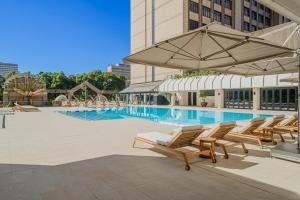 a swimming pool with lounge chairs and an umbrella at Hyatt Regency Harare The Meikles in Harare