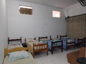 una camera con un gruppo di letti, sedie e un tavolo di POUSADA PERLLA's Pindamonhangaba a Pindamonhangaba