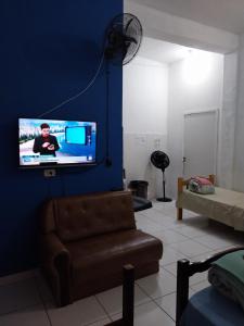 un salon avec une télévision sur un mur bleu dans l'établissement POUSADA PERLLA's Pindamonhangaba, à Pindamonhangaba