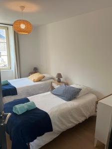 um quarto com 3 camas e lençóis azuis em La Houle em Cancale
