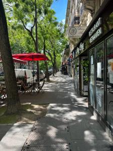 a street with tables and a red umbrella on a sidewalk at Appartement parisien (12ème) in Paris +2 photos