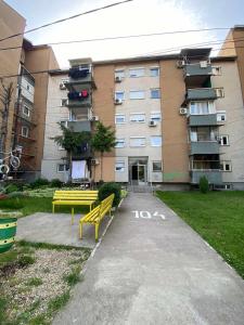 a yellow bench in front of a building at Dena Apartment in Kumanovo +3 photos