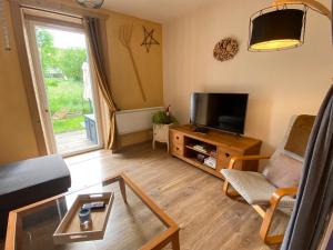 sala de estar con sofá y TV en La petite marmite du lac de Vouglans, en Pont-de-Poitte