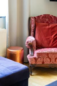 a bedroom with a red chair and a stool at De Koperen Geit in Kanne