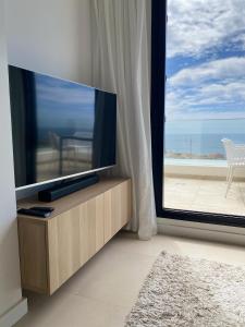 - un salon avec une télévision et une grande fenêtre dans l'établissement Heerlijk penthouse, dakterras met prachtig zeezicht, kingsize bed, zwembad, 700m van strand, à Torre de Benagalbón