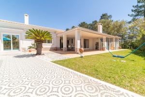 ein weißes Haus mit einem Garten und einer Auffahrt in der Unterkunft Villa das Giestas in Quinta do Conde