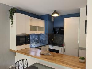 - une cuisine avec des placards blancs et des murs bleus dans l'établissement Charmant appartement de 41m2 avec linges de maison et ménage compris, 2 pièces à Lamalou-les-Bains pour 2 personnes, à Lamalou-les-Bains