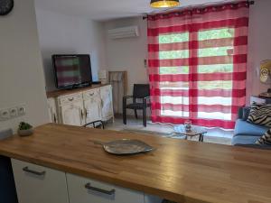 - un salon avec un rideau rouge et une télévision dans l'établissement Charmant appartement de 41m2 avec linges de maison et ménage compris, 2 pièces à Lamalou-les-Bains pour 2 personnes, à Lamalou-les-Bains