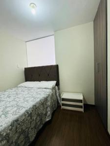 una piccola camera da letto con un letto e un comodino di Cómodo y hermoso departamento amoblado ad Arequipa