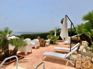 a patio with chairs and an umbrella and the ocean at Villa Luce in Siracusa