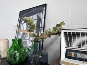 un vase vert avec des fleurs à côté d'un miroir dans l'établissement 87029house, à Scalea