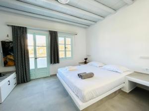 a white bedroom with a large bed and a window at Folegandros residence/Karavostasi in Karavostasi