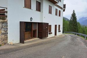 a building with wooden doors on the side of a road at La taverna dei folletti in Valle di Cadore