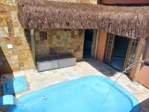 a swimming pool in a building with a thatch roof at Casa Recanto do sol in Natal